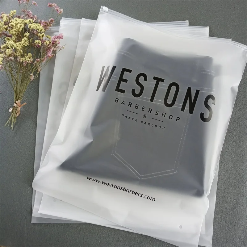 There are 4 Custom frosted ziplock bags on a gray background, the top bag contains a pair of pants.