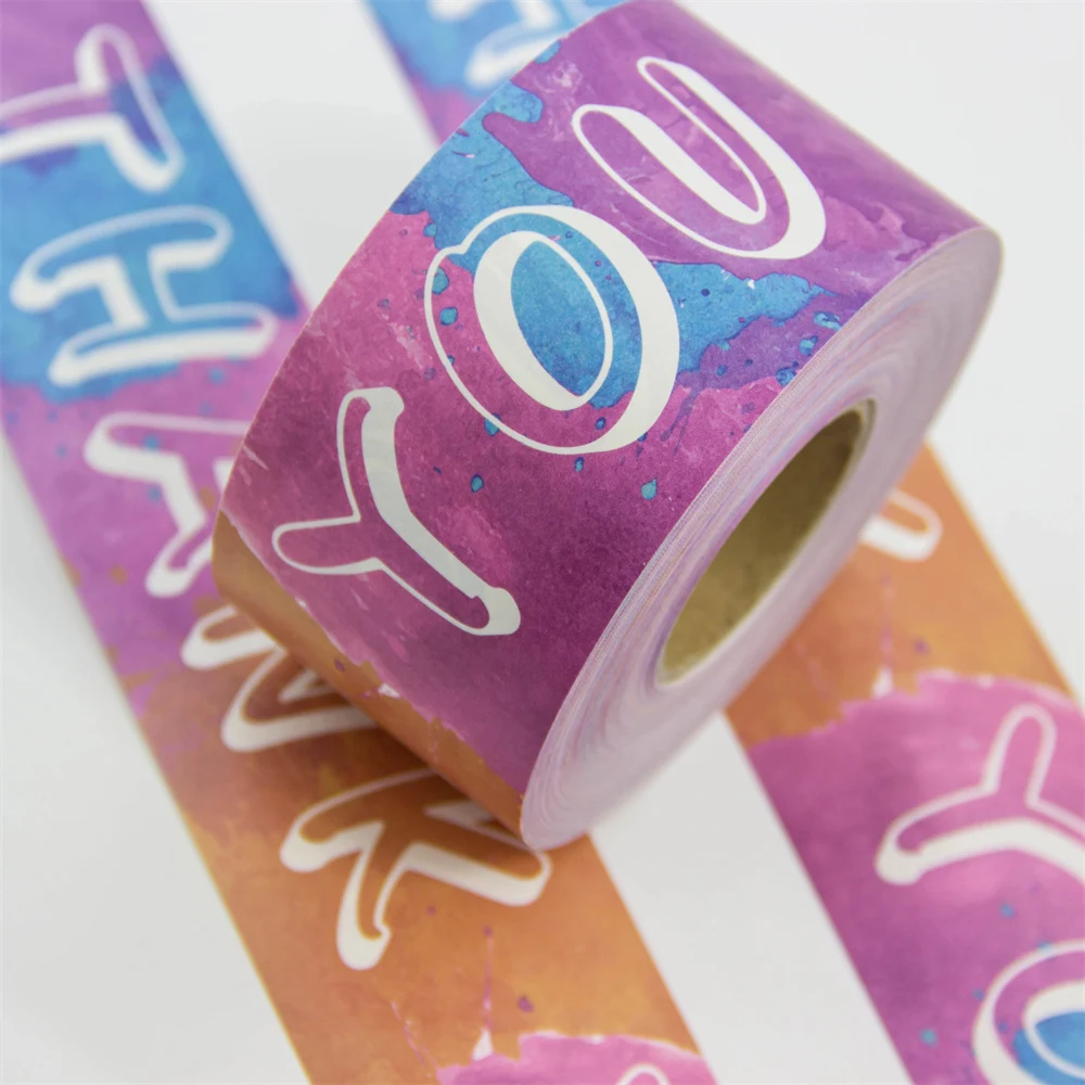 Ruban adhésif d'emballage coloré en rouleaux aux teintes violettes, bleues et orange vibrantes, présentant un motif script "Thank You" répété, sur fond blanc.