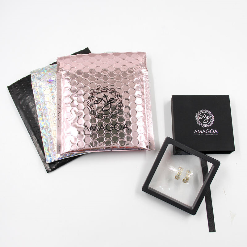 3 bubble mailers in different colors, on the right of these mailers are a jewelry box.